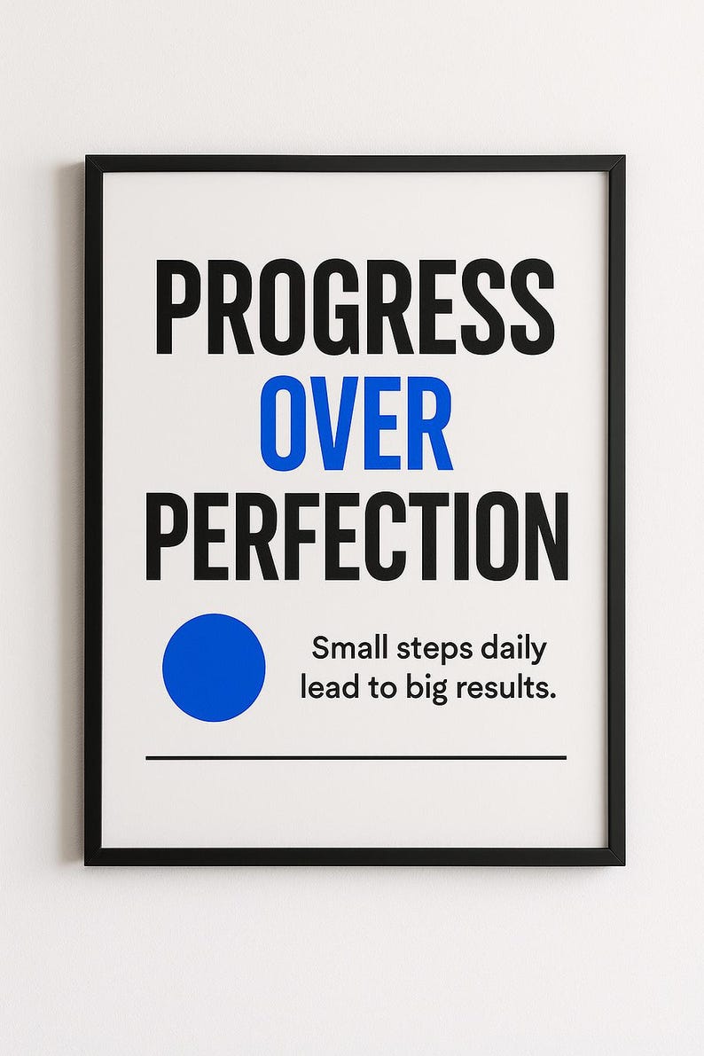 May include: A framed print with the words "PROGRESS OVER PERFECTION" in black and blue. Below the text is a blue circle and the phrase "Small steps daily lead to big results."