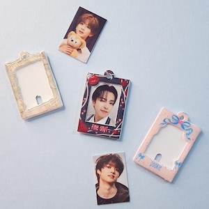 Peut inclure: Plusieurs petits porte-cartes photo et cartes photo sont dispersés sur une surface bleu clair. Les supports sont de différentes couleurs, dont le rose et le beige, et comportent des éléments décoratifs. Les cartes photo présentent des images de personnes.