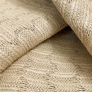 May include: Close-up of a woven fabric with a herringbone pattern. The fabric is a light beige color and has a natural, textured look.