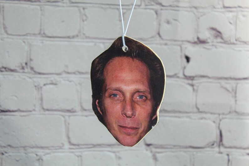 Puede incluir: Primer plano de un ambientador de coche con una foto de un hombre con cabello casta&ntilde;o y una expresi&oacute;n seria.