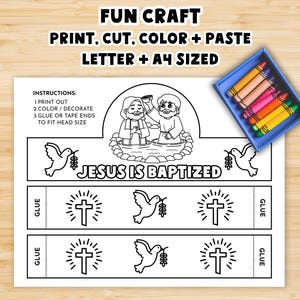May include: A black and white printable craft sheet with the text "JESUS IS BAPTIZED". The sheet includes instructions, illustrations of Jesus, doves, and crosses. A blue crayon box with colorful crayons is in the upper right corner.