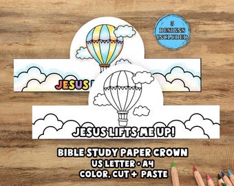 May include: Paper crown craft kit with hot air balloon designs. One crown is colored with a blue, yellow, and orange balloon, the other is a black and white outline. Text includes "JESUS" and "JESUS LIFTS ME UP!"