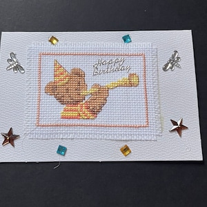 Carte de voeux joyeux anniversaire au point de croix, Teddy soufflant de la trompette