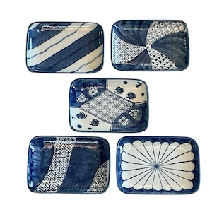 May include: Five rectangular ceramic dishes with blue and white patterns. Designs include diagonal stripes, geometric shapes, and floral motifs. The dishes are arranged against a white background, showcasing their decorative appeal.