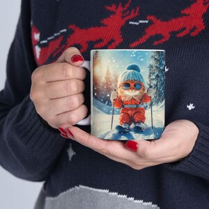 May include: White ceramic mug with a colorful image of a cat wearing a blue hat and sunglasses, skiing down a snowy mountain.