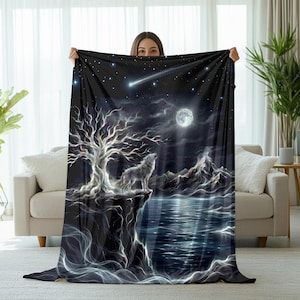 May include: A black blanket featuring a wolf howling at the moon under a starry night sky. The design includes a tree, mountains, and a reflective body of water. The blanket is held up by a person.