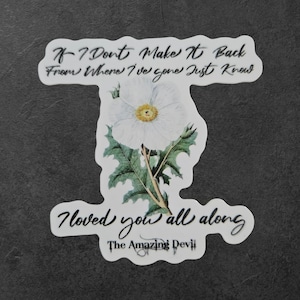Puede incluir: Una pegatina blanca con un diseño floral y texto. La pegatina presenta una flor blanca con un centro amarillo y hojas verdes. El texto dice "If I Don't Make It Back From Where I've Gone Just Know I Loved You All Along" y "The Amazing Devil."
