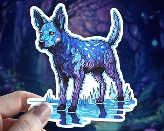 Könnte beinhalten: Ein gestanzter Aufkleber mit einem stilisierten Hund in Blau- und Violetttönen, komplexen geometrischen Mustern und leuchtend orangefarbenen Augen. Der Hund steht auf einer reflektierenden blauen Oberfläche mit kleinen, spitzen, kristallartigen Formen.