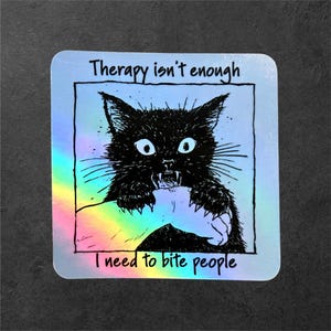 Könnte beinhalten: Ein quadratischer holografischer Aufkleber mit einer schwarzen Tuschezeichnung einer Katze, die in einen menschlichen Arm beißt. Der Text "Therapy isn't enough" steht über der Katze und "I need to bite people" steht darunter in schwarzer Schrift.