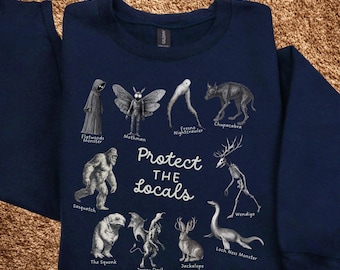 May include: Navy blue sweatshirt featuring illustrations of cryptids like Mothman, Sasquatch, and the Loch Ness Monster. The phrase "Protect the Locals" is printed in white. A unique and quirky design for fans of folklore and the unexplained.