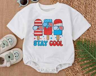 May include: White baby onesie with a graphic of three popsicles wearing sunglasses. The popsicles are red, white, and blue with stars and stripes. The text "STAY COOL" is printed below the popsicles.