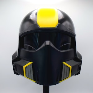 May include: A black and yellow helmet with a visor and a distinctive design. The helmet features a yellow stripe across the top and yellow accents on the sides. The helmet is likely for cosplay or costume use.