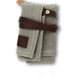 May include: A grey canvas roll-up pouch with a brown leather strap and a small leather patch with a deer logo.