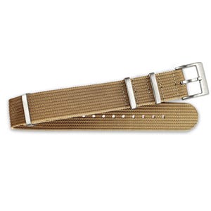 Könnte beinhalten: Ein beigefarbenes Nylon-Armband mit silberner Schließe und Bandanstößen.