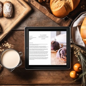 May include: Overhead shot of a wooden table with various baked goods. A tablet displays a recipe for a classic sourdough loaf. Several loaves of bread, rolls dusted with powdered sugar, and a glass of milk are arranged around the tablet.