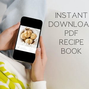 May include: A person is holding a smartphone displaying a digital recipe book for gluten-free sourdough bread. The text on the screen reads "Gluten-Free Sourdough" and "Ancient Ferments". The text on the white background behind the phone reads "INSTANT DOWNLOAD PDF RECIPE BOOK".