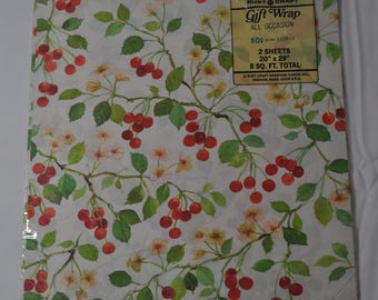 May include: Gift wrap featuring a white background with a repeating pattern of red cherries and green leaves. The text on the packaging reads "Rust Craft Gift Wrap All Occasion 800 1338-3 2 Sheets 20" x 29" 8 Sq. Ft. Total Rust Craft Greeting Cards, Inc. Dedham, Mass. 02026 U.S.A."