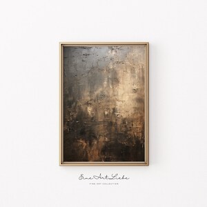 May include: Abstract painting in shades of brown, gray, and gold with a textured surface. The painting is framed in a gold frame and is hanging on a white wall. The text "Eine Art Liebe Fine Art Collection" is printed below the frame.