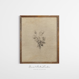 May include: A black and white line drawing of a bouquet of flowers in a simple brown frame. The drawing is on a textured beige background. The text "Eine Art Liebe" is printed below the frame.