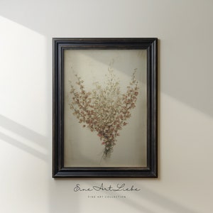 May include: A framed print of a bouquet of dried flowers in shades of brown, pink, and white. The flowers are arranged in a vase and are set against a white background. The frame is black and has a simple design.