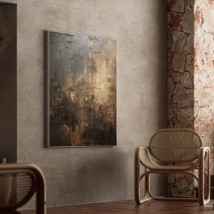 May include: A brown and gold abstract painting hangs on a wall in a room with a wicker chair and a stone wall.