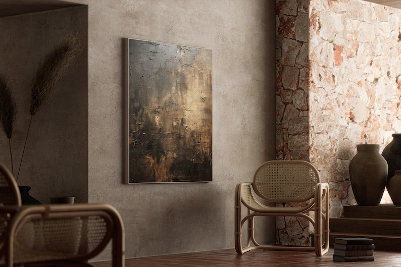 May include: A brown and gold abstract painting hangs on a wall in a room with a wicker chair and a stone wall.