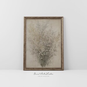 May include: A framed abstract painting with a textured, speckled design in shades of beige, brown, and green. The frame is a simple, gold-toned metal.