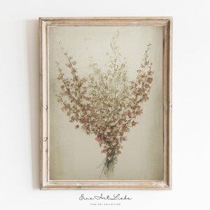 May include: A framed print of a dried flower bouquet in shades of brown, beige, and pink. The bouquet is arranged in a vase-like shape and is set against a light beige background. The frame is a simple, light wood.