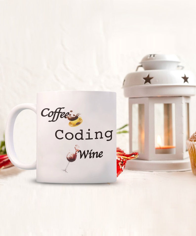 Pode incluir: Caneca de cer&acirc;mica branca com as palavras "Coffee Coding Wine" em escrita preta. A caneca apresenta ilustra&ccedil;&otilde;es de uma x&iacute;cara de caf&eacute;, um s&iacute;mbolo de codifica&ccedil;&atilde;o de computador e uma ta&ccedil;a de vinho. Uma lanterna branca e um item decorativo vermelho est&atilde;o no fundo.