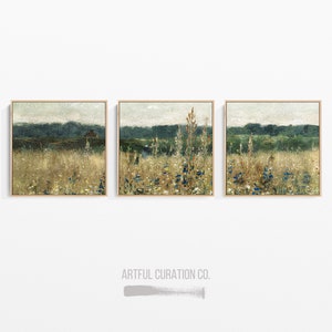 Pu&ograve; includere: Tre dipinti di paesaggio incorniciati con una tavolozza di colori tenui che raffigurano un campo di fiori selvatici e una linea di foresta lontana. I dipinti sono disposti in fila su una parete bianca.