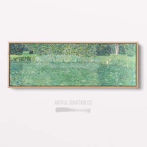 May include: A rectangular framed artwork depicting a serene waterscape. The painting features a green lake with reflections, lush green foliage, and a tree. The artwork is framed in a natural wood frame, and the text "ARTFUL CURATION CO." is visible.