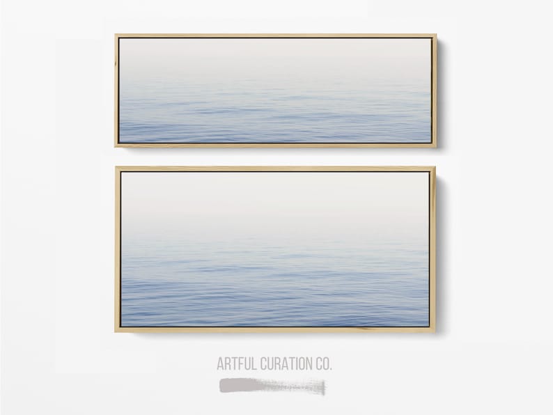 May include: Two framed wall art pieces featuring a serene ocean scene. The artwork depicts a gradient of blue and white, with subtle wave patterns. The frames are a natural wood color, adding a touch of warmth to the minimalist design.