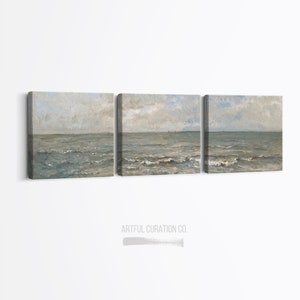 May include: A triptych of canvas art prints depicting a seascape. The artwork features a muted color palette of blues, grays, and beige, with visible brushstrokes. The ocean waves and sky are the primary subjects. The text "ARTFUL CURATION CO." is at the bottom.