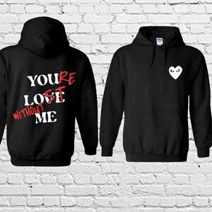 May include: Black hooded sweatshirt with a white heart with eyes on the front and the text "YOU'RE LOST WITHOUT ME" in red and white on the back.