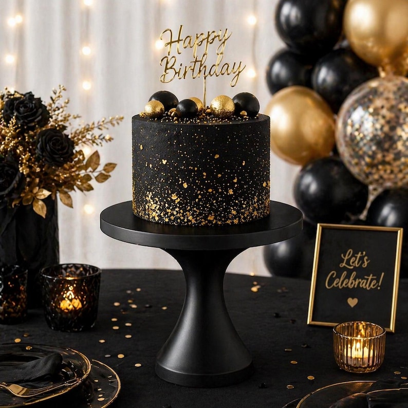 May include: A black birthday cake with gold sprinkles and a "Happy Birthday" cake topper sits on a black cake stand. The cake is surrounded by black and gold balloons, candles, and a sign that says "Let's Celebrate!"