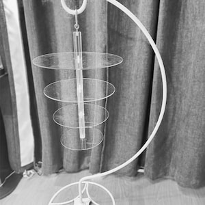 May include: White metal cake stand with a circular base and a curved arm that holds a four-tier acrylic cake stand.