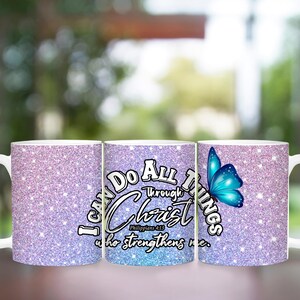 May include: Two white ceramic mugs with a glittery pink and blue design. The mug on the right has a blue butterfly and the text "I can do all things through Christ who strengthens me." The mug on the left has the same design but without the butterfly.