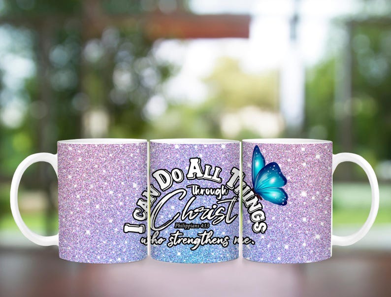 May include: Two white ceramic mugs with a glittery pink and blue design. The mug on the right has a blue butterfly and the text "I can do all things through Christ who strengthens me." The mug on the left has the same design but without the butterfly.