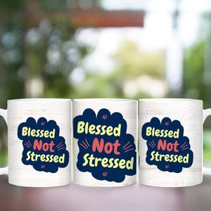 May include: Three white ceramic mugs with a woodgrain pattern. Each mug has a blue and yellow cloud with the text "Blessed Not Stressed" in pink and blue lettering.