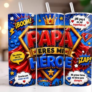 May include: A blue tumbler with a superhero theme, featuring the words "PAPA ERES MI HEROE" in red and blue. The design includes comic book style exclamations, a crown, and the phrases "Mi papá es mi superhéroe!" and "Mi primer héroe, mi héroe para siempre."