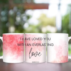 May include: Two white ceramic mugs with a pink watercolor background. The text on the mugs reads "I have loved you with an everlasting love Jeremiah 31:3".