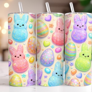 Op de afbeelding: Een beker met een rietje heeft een herhaald patroon van pastelkleurige paashazen en eieren. De konijntjes zijn blauw, roze, paars en groen, met glinsterende details. De eieren zijn versierd met kleurrijke patronen en omringd door snoephartjes en bloemen.