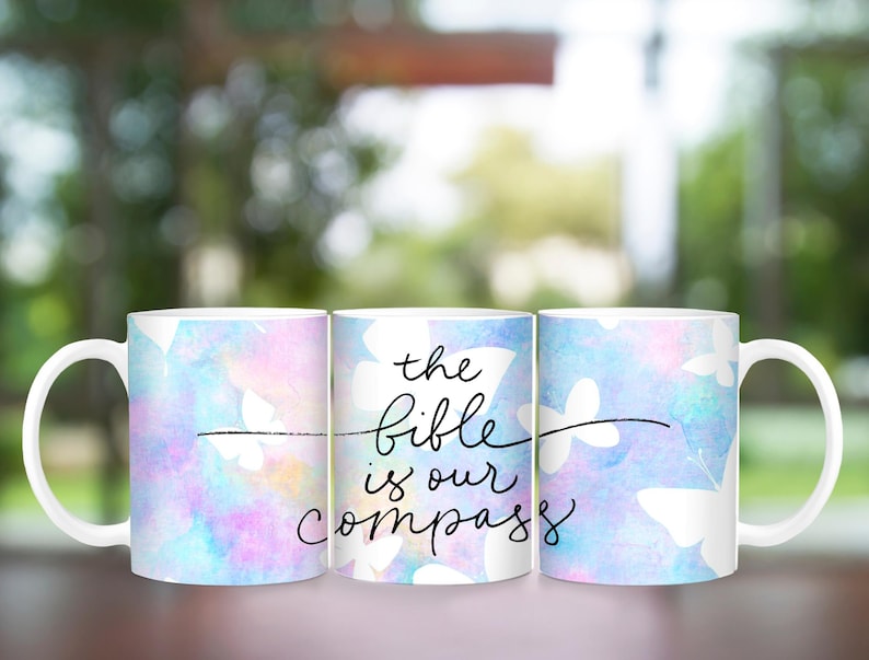 May include: Three white ceramic mugs with a watercolor-style background of blue, pink, and purple. The middle mug has the text "the bible is our compass" in black.