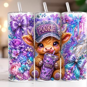 May include: A cylindrical tumbler with a straw featuring a colorful graphic of a fluffy highland cow wearing a cap labeled POOKIE, holding a matching purple cup labeled POOKIE, surrounded by purple flowers, butterflies, and bows.