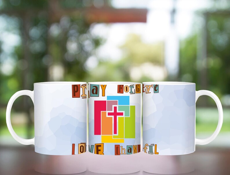 May include: Three white ceramic mugs with a colorful design featuring the words "Pray Forgive Love Thankful" and a cross in the center. The mugs are arranged in a row on a table.