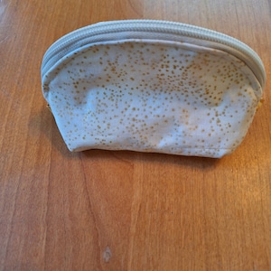 May include: A white zippered pouch with a gold glitter pattern.