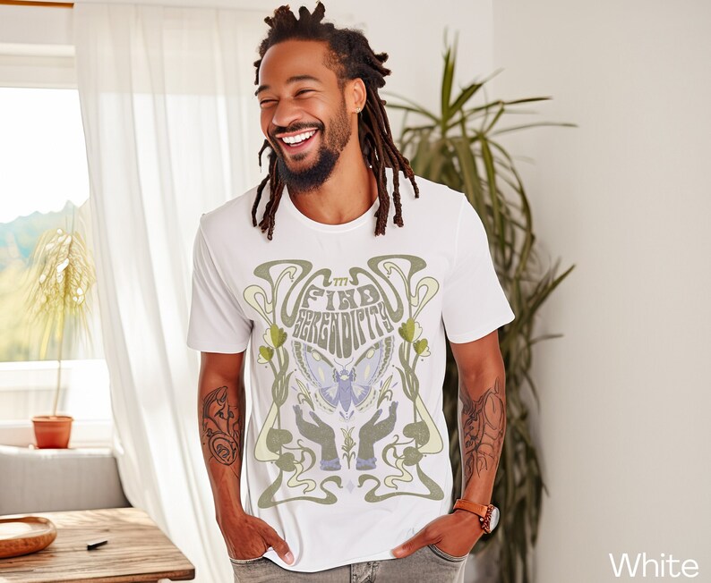 K&ouml;nnte beinhalten: Wei&szlig;es T-Shirt mit einem grafischen Design mit einem Schmetterling, H&auml;nden und dem Text "Find Serendipity".