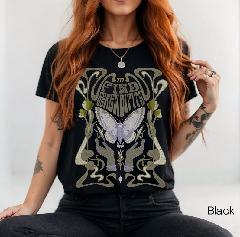 K&ouml;nnte beinhalten: Schwarzes T-Shirt mit einem grafischen Aufdruck eines Schmetterlings, Blumen und dem Text "Find Serendipity".