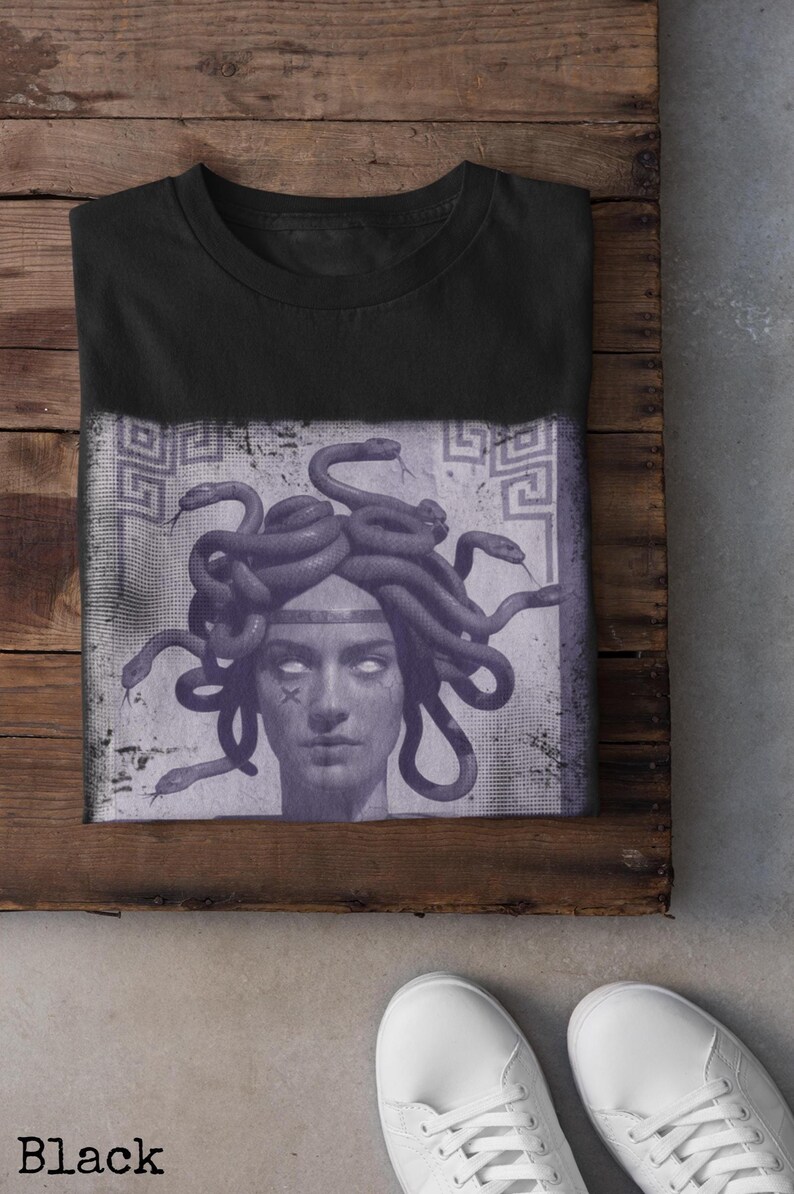 May include: Black t-shirt featuring a Medusa graphic. The design shows a detailed illustration of Medusa's face with snakes for hair, set against a faded, textured background. The word "Black" is printed at the bottom.