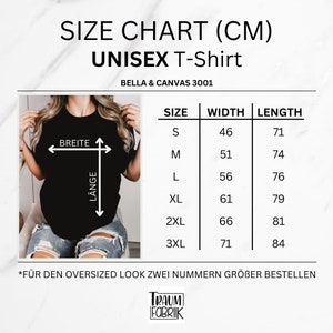 Może przedstawiać: Tabela rozmiar&oacute;w dla koszulki unisex w centymetrach. Tabela pokazuje szerokość i długość dla rozmiar&oacute;w S, M, L, XL, 2XL i 3XL. Tekst "*F&Uuml;R DEN OVERSIZED LOOK ZWEI NUMMERN GR&Ouml;BER BESTELLEN" znajduje się na dole tabeli.